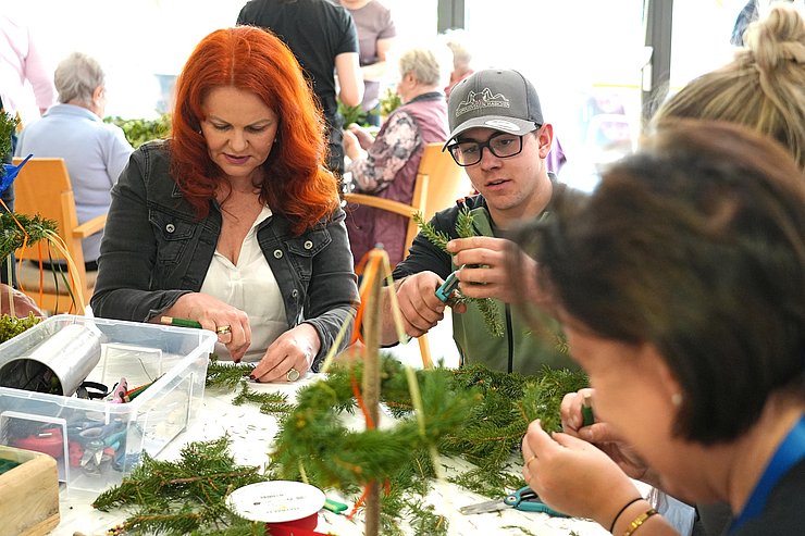 LRin Hagele sitzt an Tisch, hilft bei Kränze binden