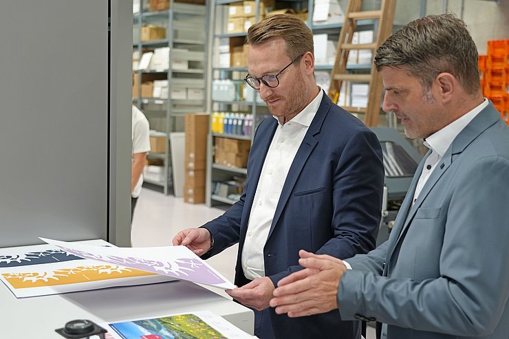 © Land Tirol/Reiter Zwei Männer schauen sich eine Drucksorte an.