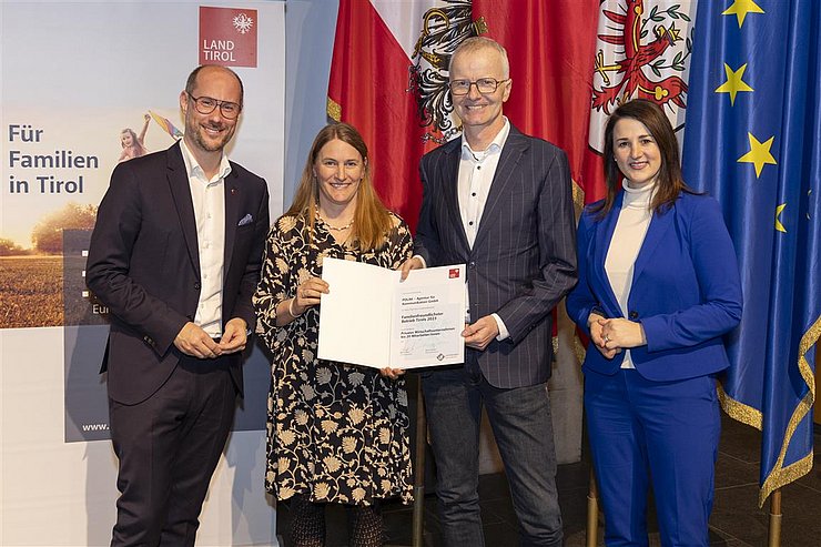 vier Personen mit Urkunde