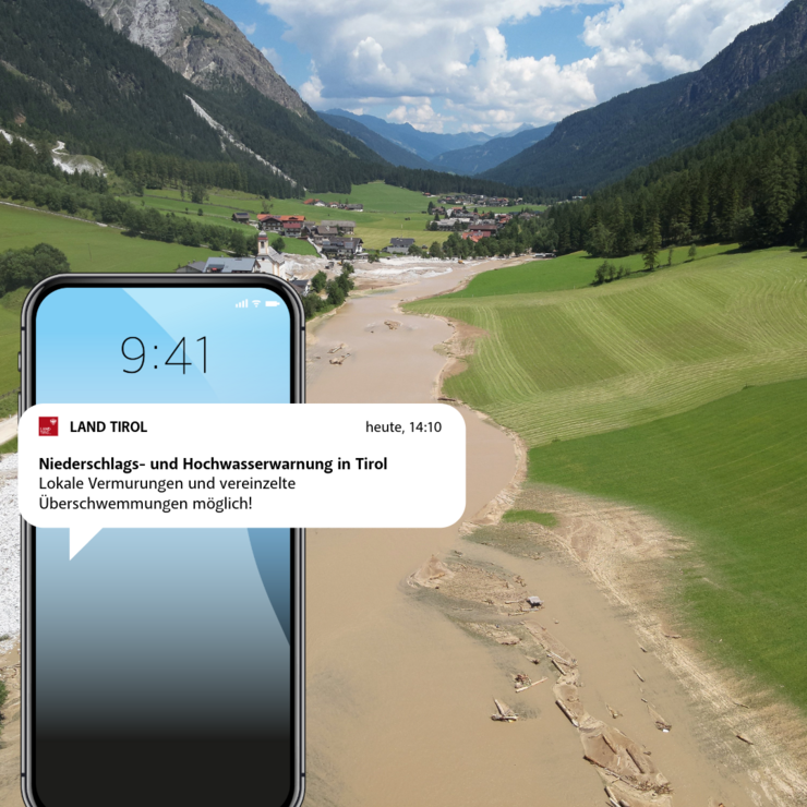 © Land Tirol Handy mit Nachricht, im Hintergrund Foto von Überschwemmung