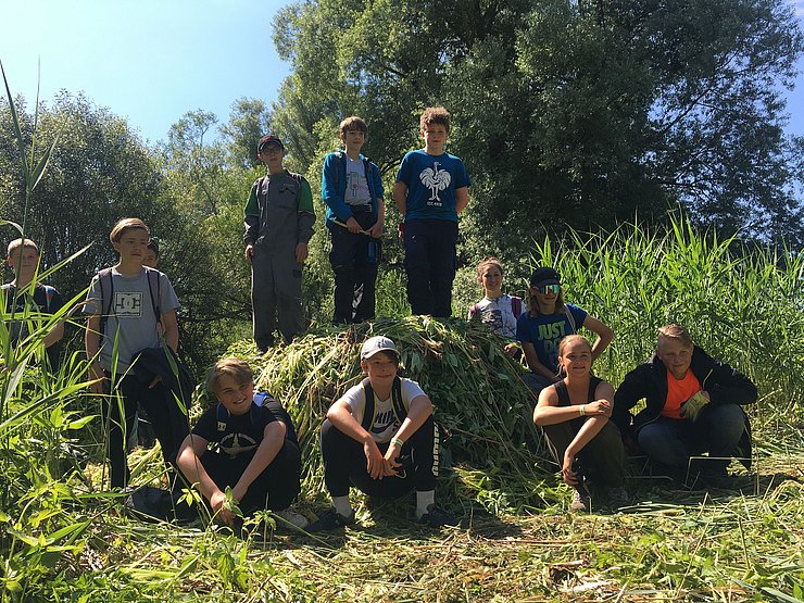 © NP Tiroler Lech/Winkelmair Schülerinnen vor einem Haufen aus ausgerissenen Pflanzen