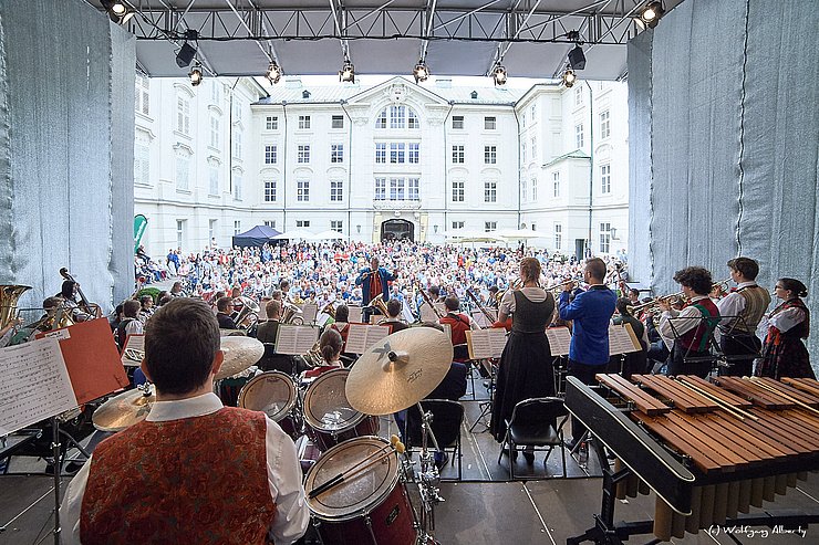 Ein Tribüne und mehrere MusikerInnen sind zu sehen.