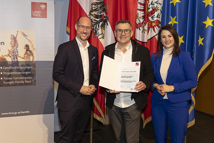 drei Personen mit Urkunde