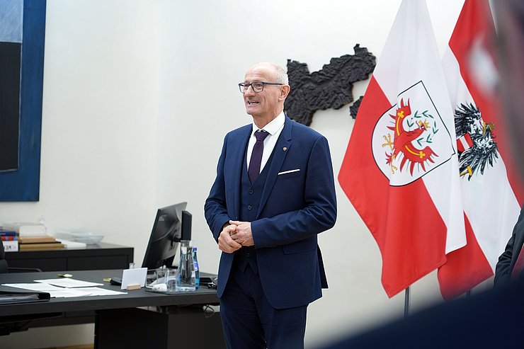 © Land Tirol/Neuner Landeshauptmann Mattle steht vor Fahnen und hält eine Rede.