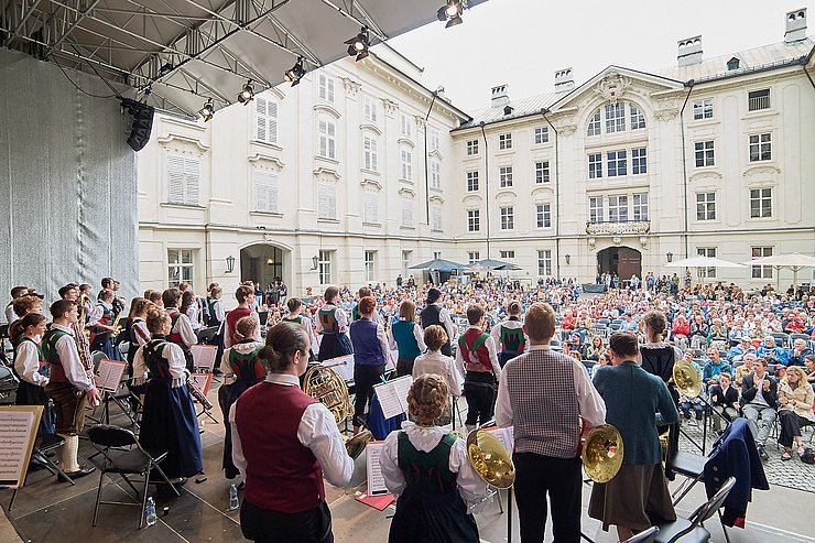 © Wolfgang Alberty Bild vom Konzert mit den Musikerinnen und Musikern auf der Bühne und vor der Bühne mit vielen Zuschauerinnen und Zuschauern im Innenhof der Innsbrucker Hofburg.