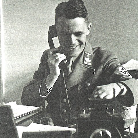 Der stellvertretende Gauleiter von Tirol-Vorarlberg sitzt an seinem Schreibtisch im Landhaus in NS-Uniform und telefoniert.