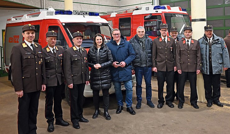 Gruppenfoto; im Hintergrund zwei Feuerwehrfahrzeuge