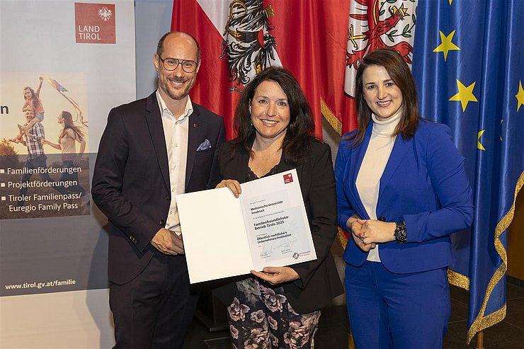 drei Personen mit Urkunde