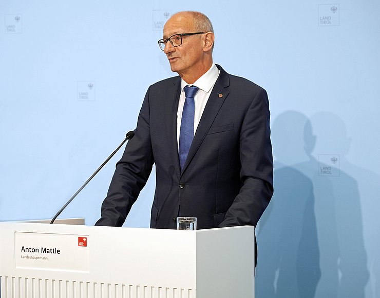 © Land Tirol/Neuner LH Anton Mattle steht hinter einem Pult und spricht zu den JournalistInnen.