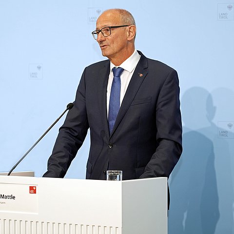 LH Anton Mattle steht hinter einem Pult und spricht zu den JournalistInnen.