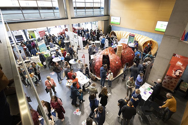 BesucherInnen - Blick von oben auf Raum mit Ausstellungsgegenständen