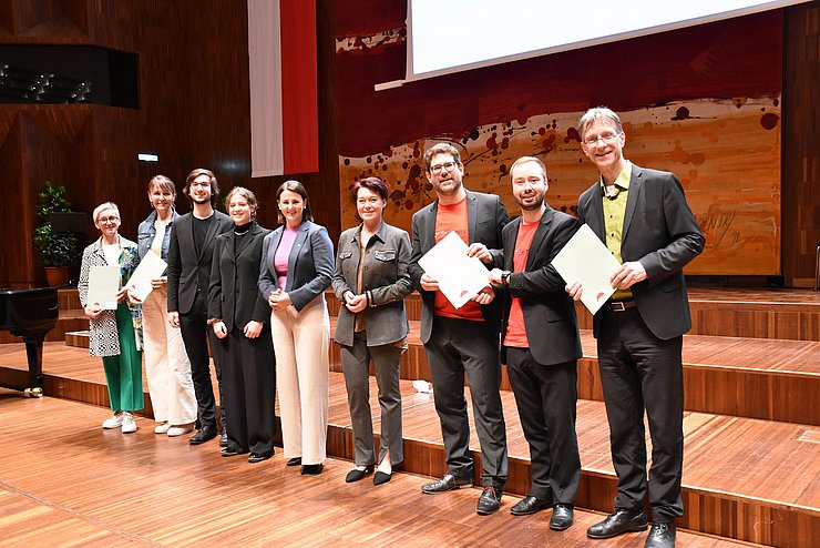 Gruppenfoto der Chorleiter mit Jugendlandesrätin Astrid Mair und Landtagspräsidentin Sonja Ledl-Rossmann: Alle stehen auf der Bühne im Saal Tirol des Congress Innsbruck, als Wandschmuck hinten die Landesfahne.