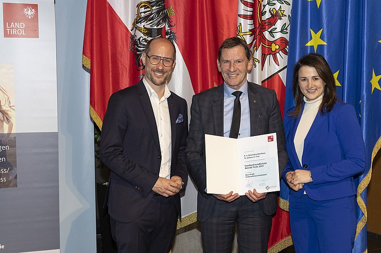 drei Personen mit Urkunde