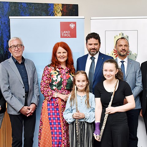 Gruppenfoto von sechs Erwachsenen und zwei Jugendlichen, die eine Querflöte in der Hand halten.