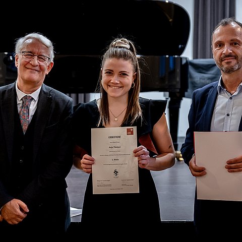 Landesmusikdirektor Helmut Schmid (r.) und Johann Bair (Prof.-Dr.-Kurt-Ebert-Stiftung) gratulieren Anja Theiner zum Hauptpreis beim Kurt-Ebert-Klavierwettbewerb.
