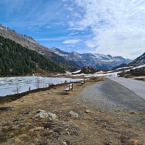 Bild vom Staller Sattel mit der Straße rechts und einem See links.