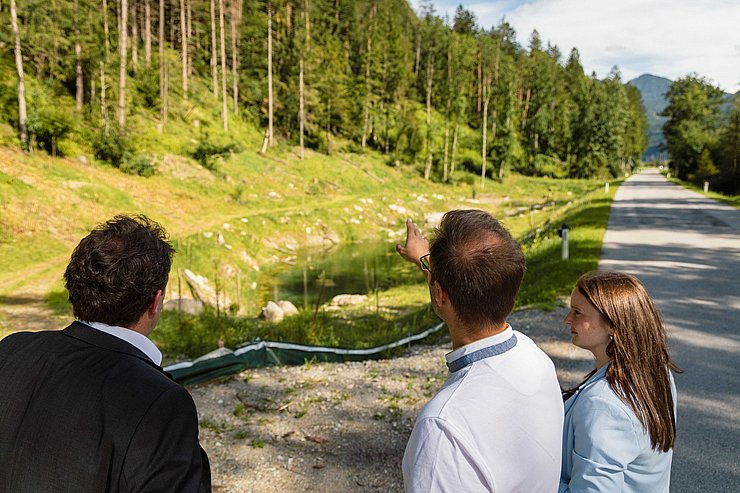 © Land Tirol Der Landesrat, Guggenberger und Holzer schauen sich die Straße entlang des Teiches an