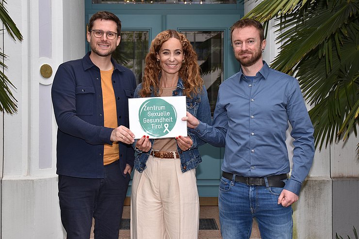 Personen stehen nebeneinander, halten Schild mit Aufschrift "Zentrum Sexuelle Gesundheit Tirol"