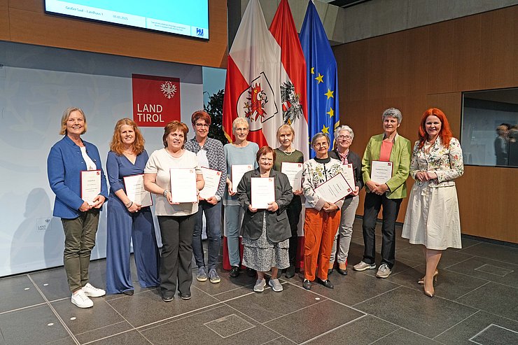 © Land Tirol/Reiter Mehrere Menschen posieren vor Flaggen.