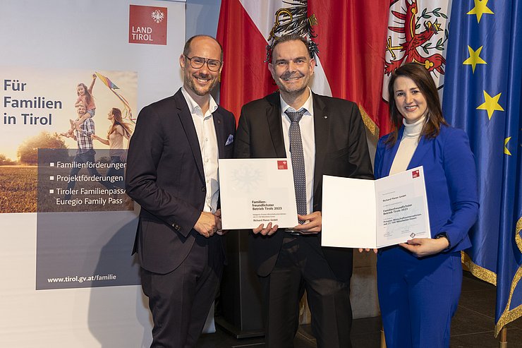 drei Personen mit Urkunde