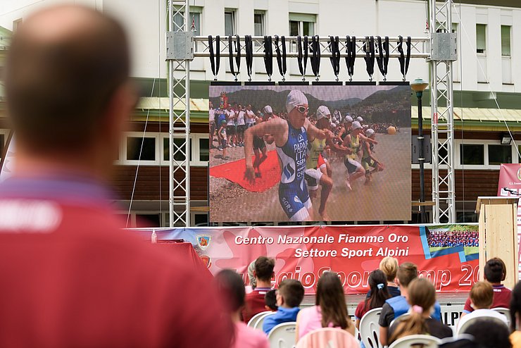 Die Jugendlichen verfolgen ein Video der Staatspolizei-Sportgruppe auf einer Leinwand. 