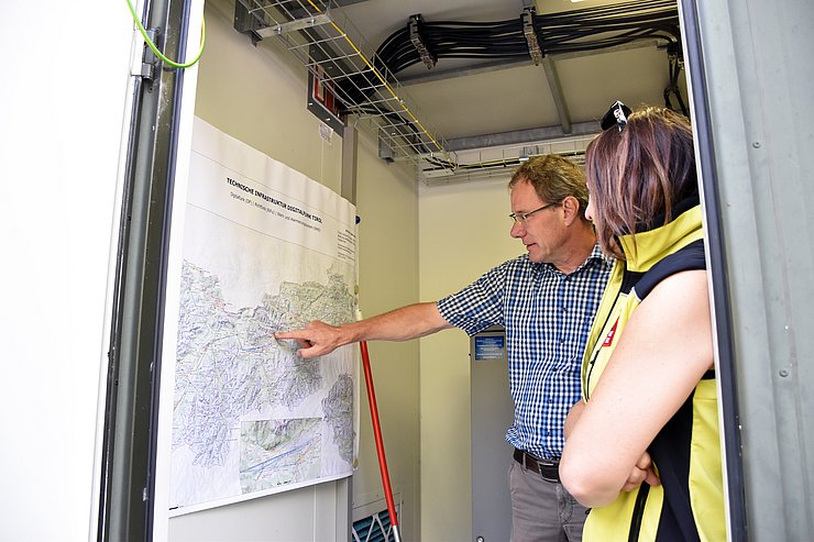 Mair und Angerer in einem Container auf eine Karte von Tirol blickend