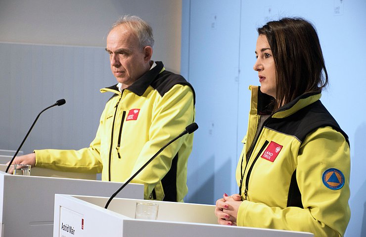 Mair und Rizzoli in gelben Jacken bei der PK stehend