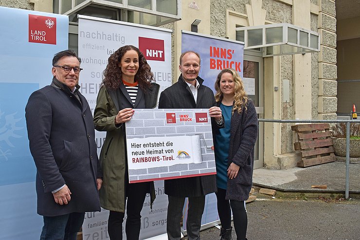 Personenfoto vor neuen Räumlichkeiten, mit Rollups Land, Stadt und NHT sowie Schild