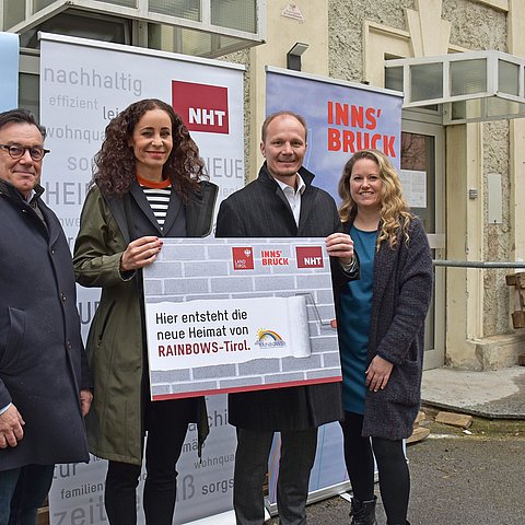 Personenfoto vor neuen Räumlichkeiten, mit Rollups Land, Stadt und NHT sowie Schild