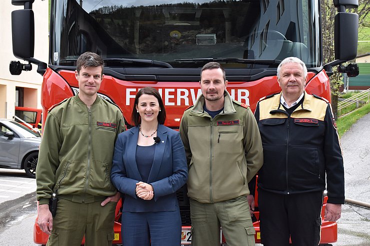 Gruppenfoto mit Muigg, Mair, Rastner und Gruber. Sie stehen vor einem roten Feuerwehr-Fahrzeug. Muigg und Rastner haben eine grüne Feuerwehr-Uniform an, Mair einen blauen Blazer und Gruber eine schwarze Feuerwehr-Uniform mit gelber Schulterpartie