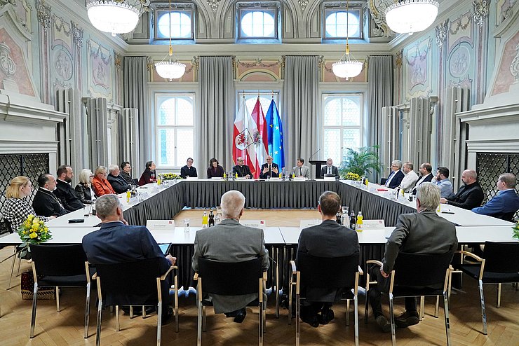 Mehrere Personen sitzen an in einem Viereck angeordneten Tischen im Parissaal.