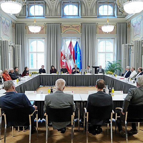 Mehrere Personen sitzen an in einem Viereck angeordneten Tischen im Parissaal.