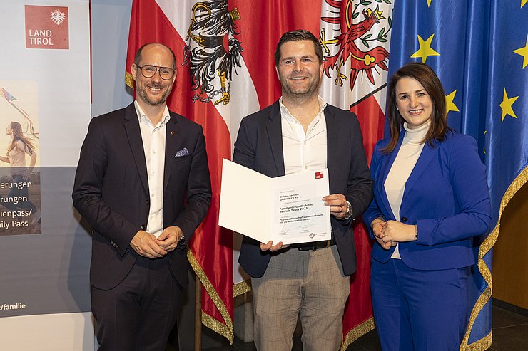 drei Personen mit Urkunde