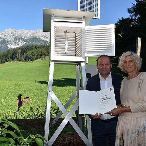 Josef Geisler und Angelika Leoni stehen mit der Urkunde vor der Messstelle.