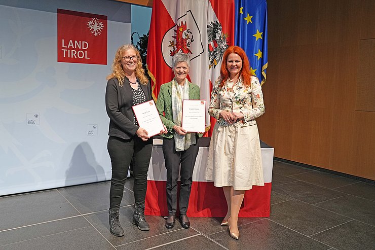 © Land Tirol/Reiter Mehrere Menschen posieren vor Flaggen.