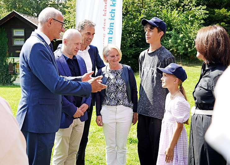 Mehrere Erwachsene unterhalten sich mit den ukrainischen Kindern.