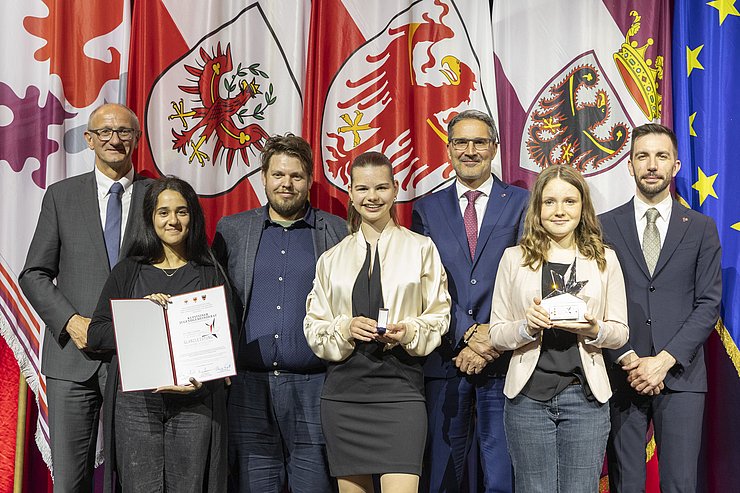 Gruppenfoto, auf dem drei junge Frauen eine Auszeichnung erhalten. 