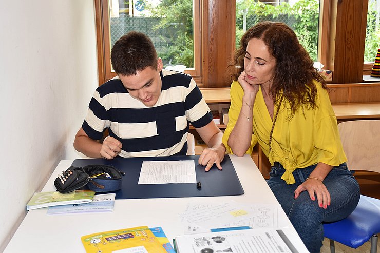 LRin sitzt neben Klienten, der Rechenaufgaben auf einem Blatt Papier macht
