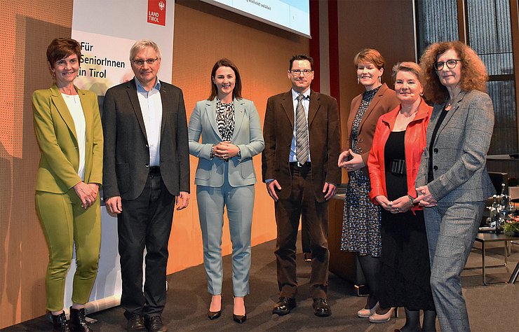 © Land Tirol/Schwarz Zur Eröffnung der SeniorInnenenquete stehen in der Messehalle von links im Halbkreis: Karin Ziegner, SelbA, Demenzexperte Prof. Josef Marksteiner, LRin Astrid Mair, Altersforscher Prof. Marc Luy, Angelika Stegmayr, Erwachsenenbildung Diözese Innsbruck, Moderatorin Pia Krismer und Ines Bürgler, Vorständin Landesabteilung Gesellschaft und Arbeit.