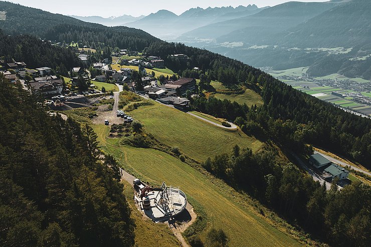 © Region Seefeld/Mathias Obmascher Drohnenaufnahme von oben - man sieht die Friedensglocke mit Aussichtsplattform und dahinter einen Teil des Dorfs