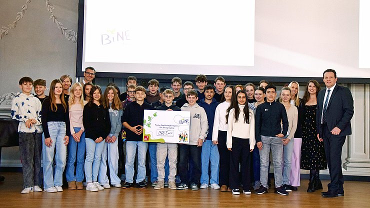 Eine ganze Mittelschulklasse steht auf der Bühne, dazwischen stehen Lehrpersonen und Landesrat Zumtobel.