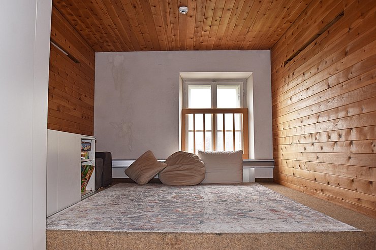 Sitzecke vor Fenster, Wände sind mit Holz tapeziert