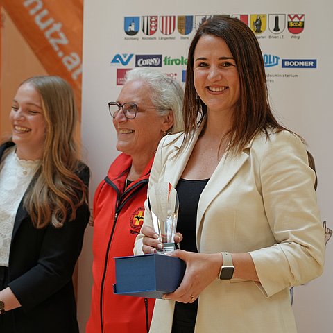 Eine Frau hält einen Pokal in der Hand.