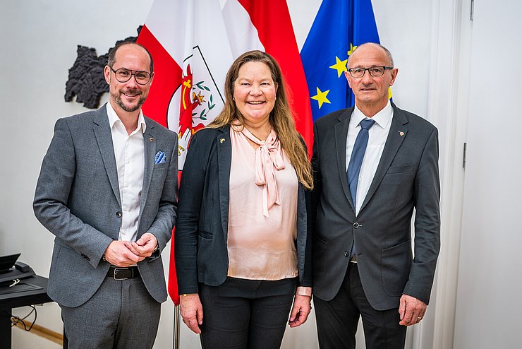 © Land Tirol Die drei Personen nebeneinander stehend im Büro des Landeshauptmannes