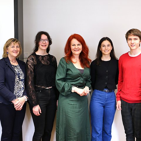 Vier Jugendliche und drei Erwachsene posieren in einem Büro für ein Foto