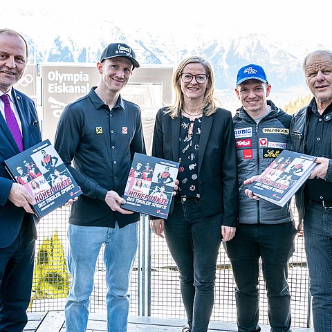 Gruppenfoto im Freien; Personen halten Sportjahrbuch in Händen
