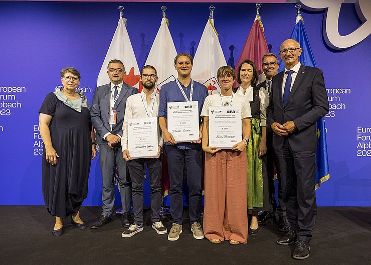 © Land Tirol/Sedlak Mehrere Personen stehen vor den Flaggen der Euregio, die mittleren drei halten Urkunden.