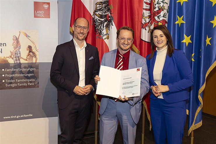 drei Personen mit Urkunde