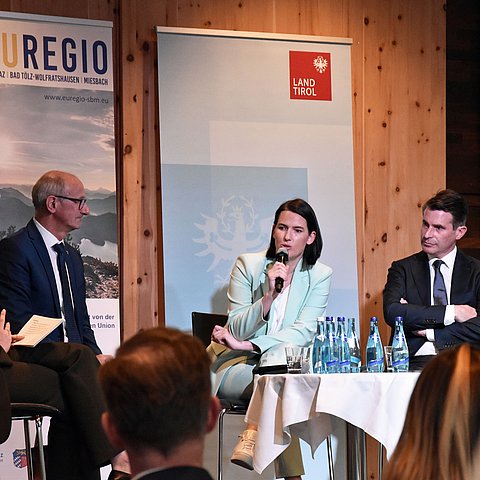 Mattle, Thaler und Beißwenger auf Bühne sitzend, Thaler mit Mikrofon sprechend