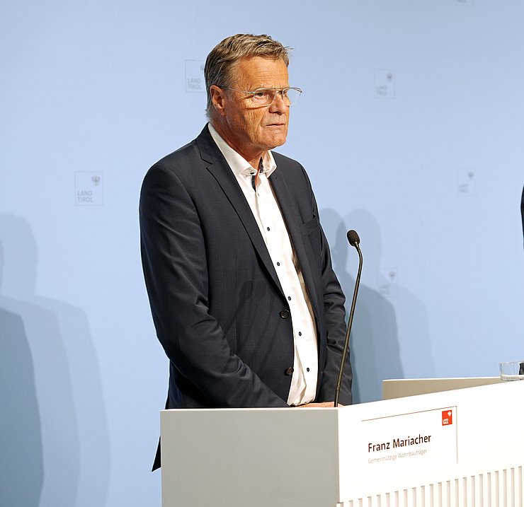 © Land Tirol/Neuner Franz Mariacher steht hinter einem weißen Pult und spricht mit den JournalistInnen.